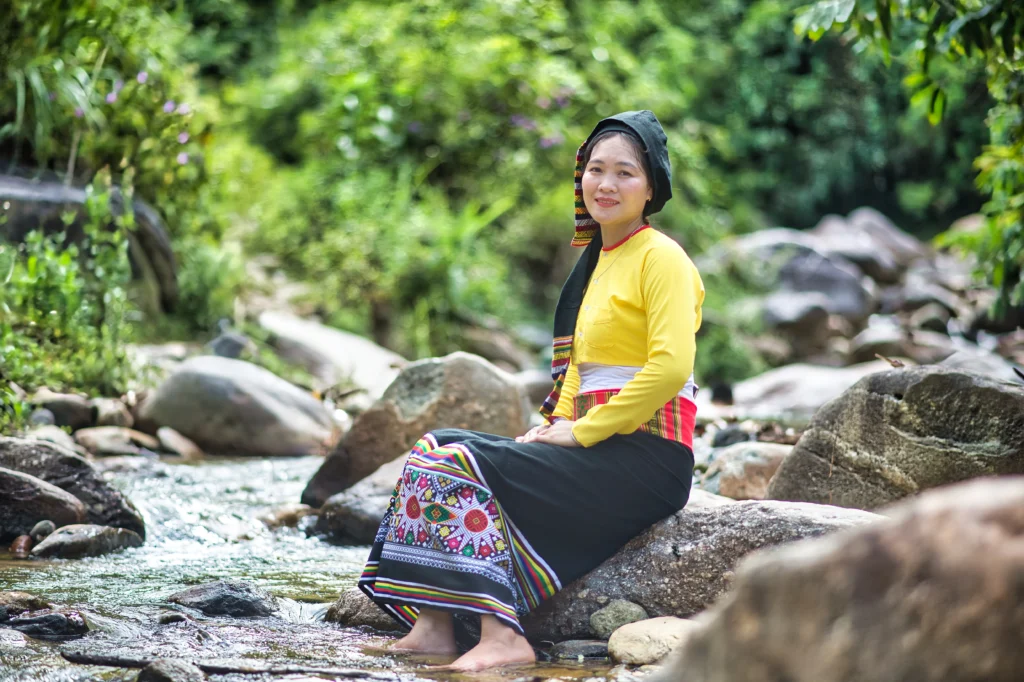 Cô gái Thái bên dòng suối trong lành, gợi lên vẻ đẹp văn hóa và thiên nhiên của làng cổ Tân Hùng.